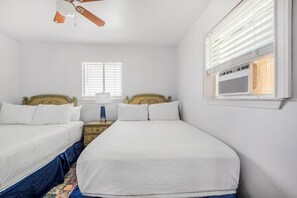 A bedroom with two beds, a ceiling fan, a nightstand, a lamp, and a window with blinds. - 🏖️ Beachfront Salt and Grace: Direct Gulf Access + Balcony + Dog Friendly (Fort Morgan)