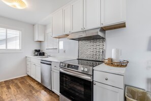 Une cuisine moderne avec des meubles blancs, une cuisinière en acier inoxydable et un pare-feu décoratif.