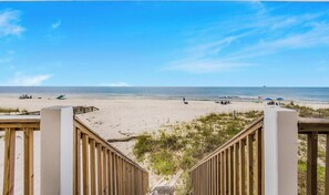 A wooden boardwalk leading to a sandy beach with umbrellas and beach chairs. - 🏖️ Beachfront Salt and Grace: Direct Gulf Access + Balcony + Dog Friendly (Fort Morgan)