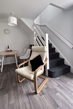 A modern interior with a wooden rocking chair, a staircase, and a dining area. - Cosy, Comfortable 3bd holiday cottage set on Tolroy, Hayle. (Tolroy Manor Hayle)