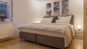 A bedroom with a bed, a window with flowers, and three wall art pieces. - Vrbo Property (Ettenheim)