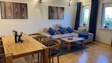 Ein modernes Wohnzimmer mit Sofa, Couchtisch und Esstisch.
