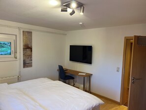 A bedroom with a bed, a desk, a chair, a television, and a door. - Peaceful premium flat (140 sq m), garden, sauna, near Europark and Black Forest (Ettenheim)