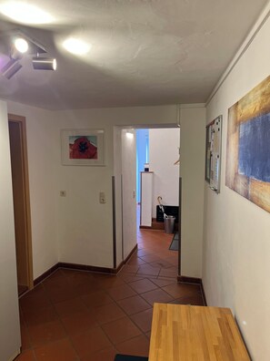 A hallway with a wooden table, a door, a framed picture, and a wall-mounted light fixture. - Peaceful premium flat (140 sq m), garden, sauna, near Europark and Black Forest (Ettenheim)