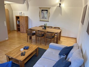 A cozy living area with a wooden dining table, four chairs, a sofa, and a small coffee table. - Peaceful premium flat (140 sq m), garden, sauna, near Europark and Black Forest (Ettenheim)