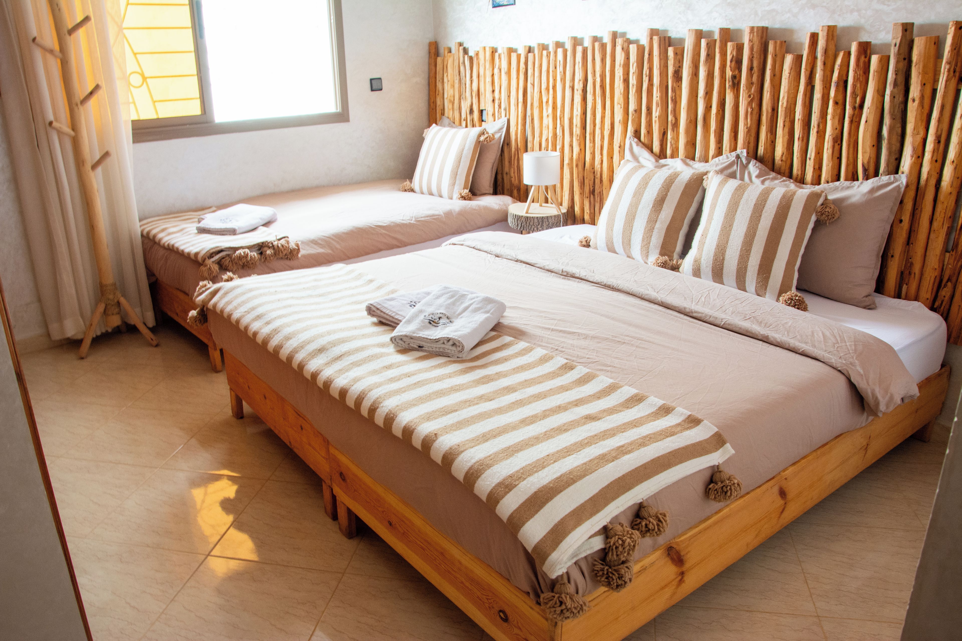 Una cama doble con estructura de madera y cabecera de listones verticales.