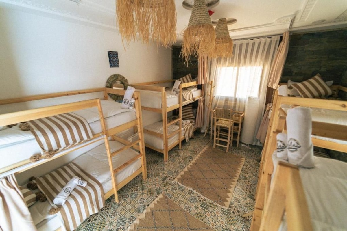 Ein Zimmer mit Etagenbetten, einem Schreibtisch und einem Stuhl.