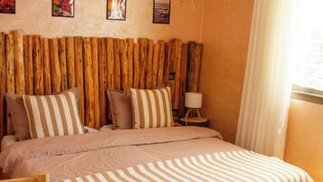 A bedroom with a wooden bed, a woven headboard, and a hanging light fixture.