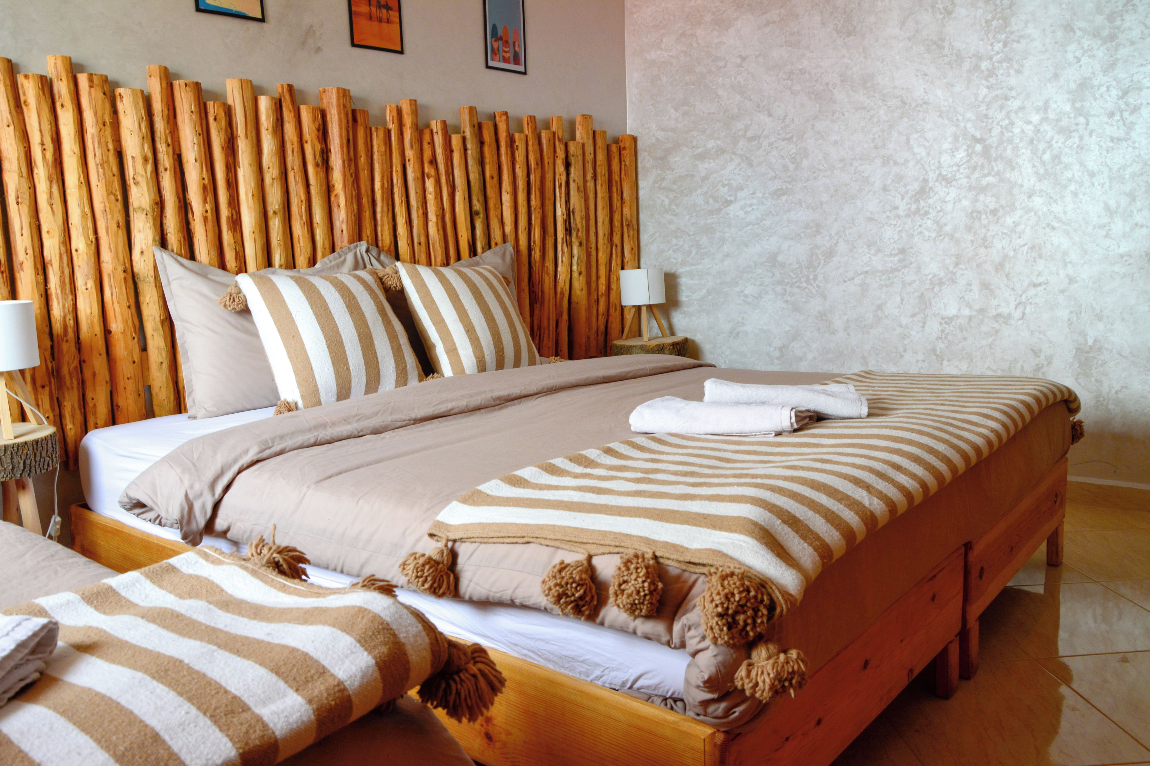 A hotel room with a wooden headboard, a bed with striped bedding, and a bedside table with a lamp.