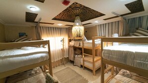 Une chambre avec des lits superposés, un plafond décoré et un luminaire suspendu.
