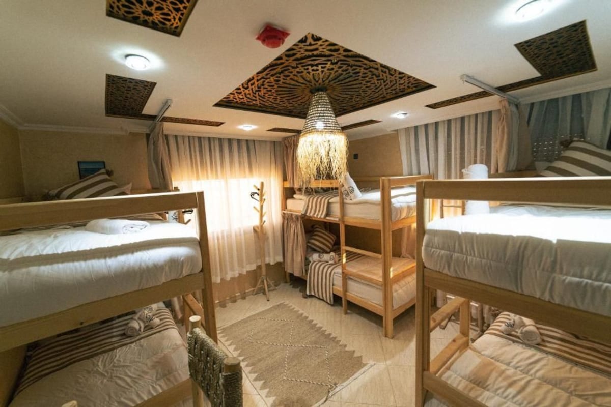 Ein Zimmer mit Etagenbetten, einer gemusterten Decke und einer hängenden Leuchte.