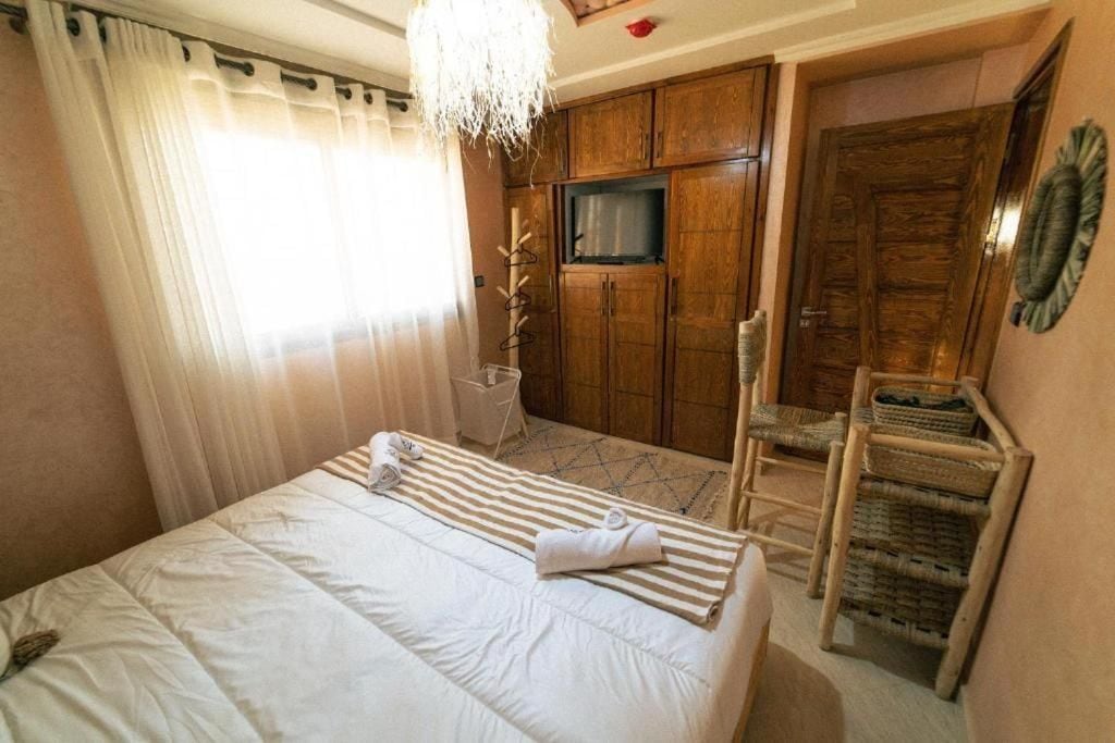 A hotel room with a bed, a television, wooden cabinets, and a door.
