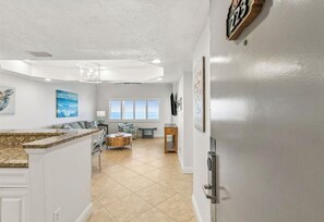 A spacious kitchen with a granite countertop, a dining area with a bench, and a view of the ocean through large windows.