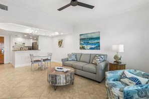 A modern living room with a sofa, a round coffee table, and a dining area with chairs.