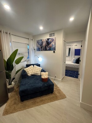 A compact living space with a sofa, a painting of an elephant, a plant, and a small table with a candle. - Cozy 1-bedroom apartment in fantastic Fort Lauderdale with AC (Fort Lauderdale)