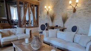 Ein rustikales Interieur mit einem Holztisch, weißen Sofas und Wandleuchten.