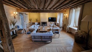 Ein großzügiges Wohnzimmer mit Kamin, Holzbalken und einem großen Fernseher.