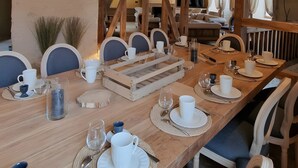 Ein Essbereich mit einem langen Holztisch, der für eine Mahlzeit gedeckt ist und von Stühlen umgeben ist.
