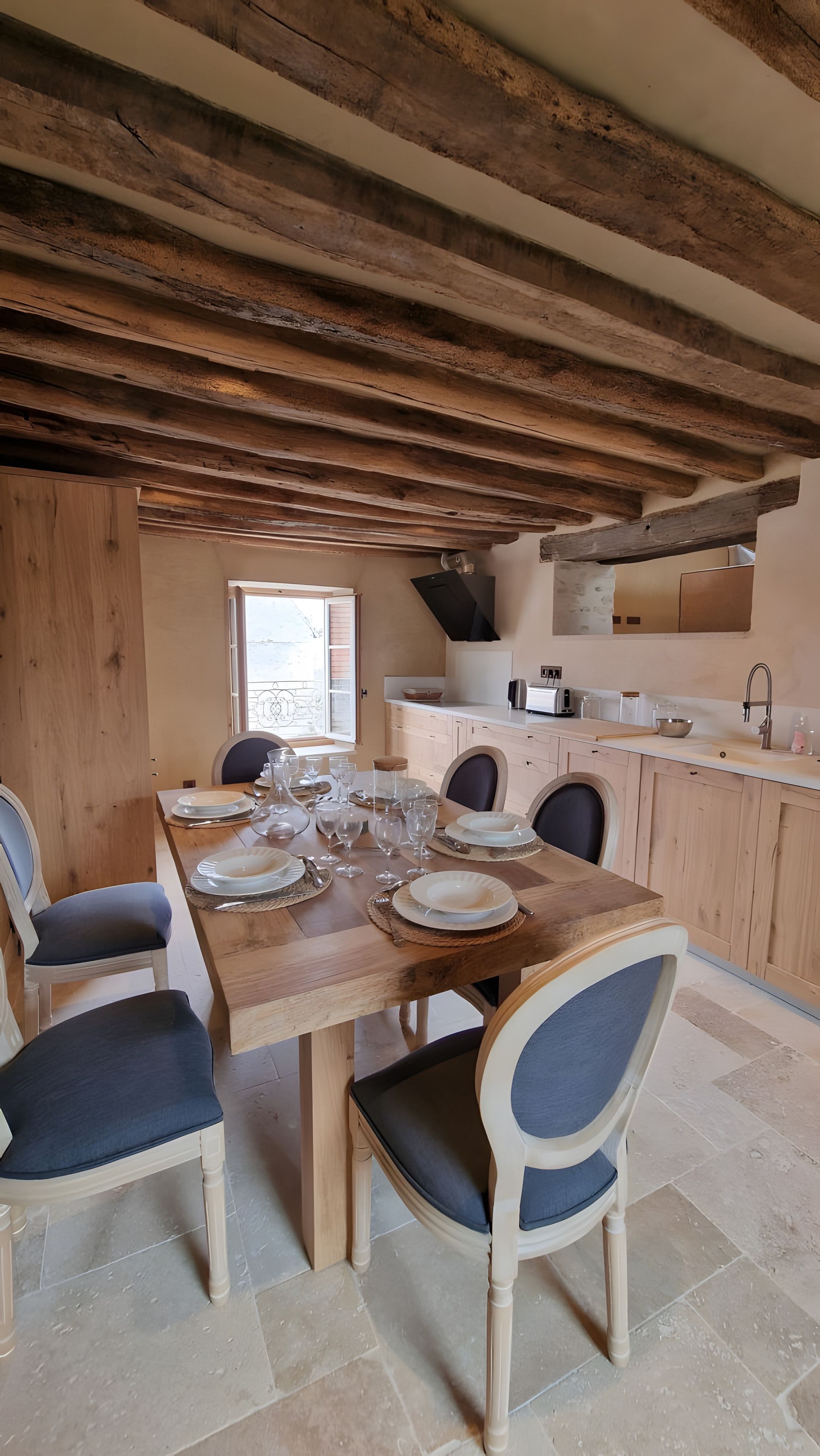 Un coin repas avec une table en bois dressée pour six personnes, entourée de chaises dotées d’assises rembourrées.