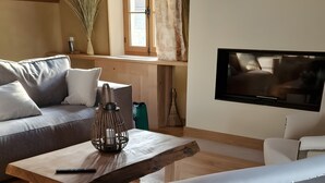 Una sala de estar acogedora con un sofá, una mesa de centro de madera y un televisor.