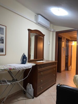 Ein Zimmer mit einem hölzernen Schminktisch, einem Bügelbrett und einem Spiegel.