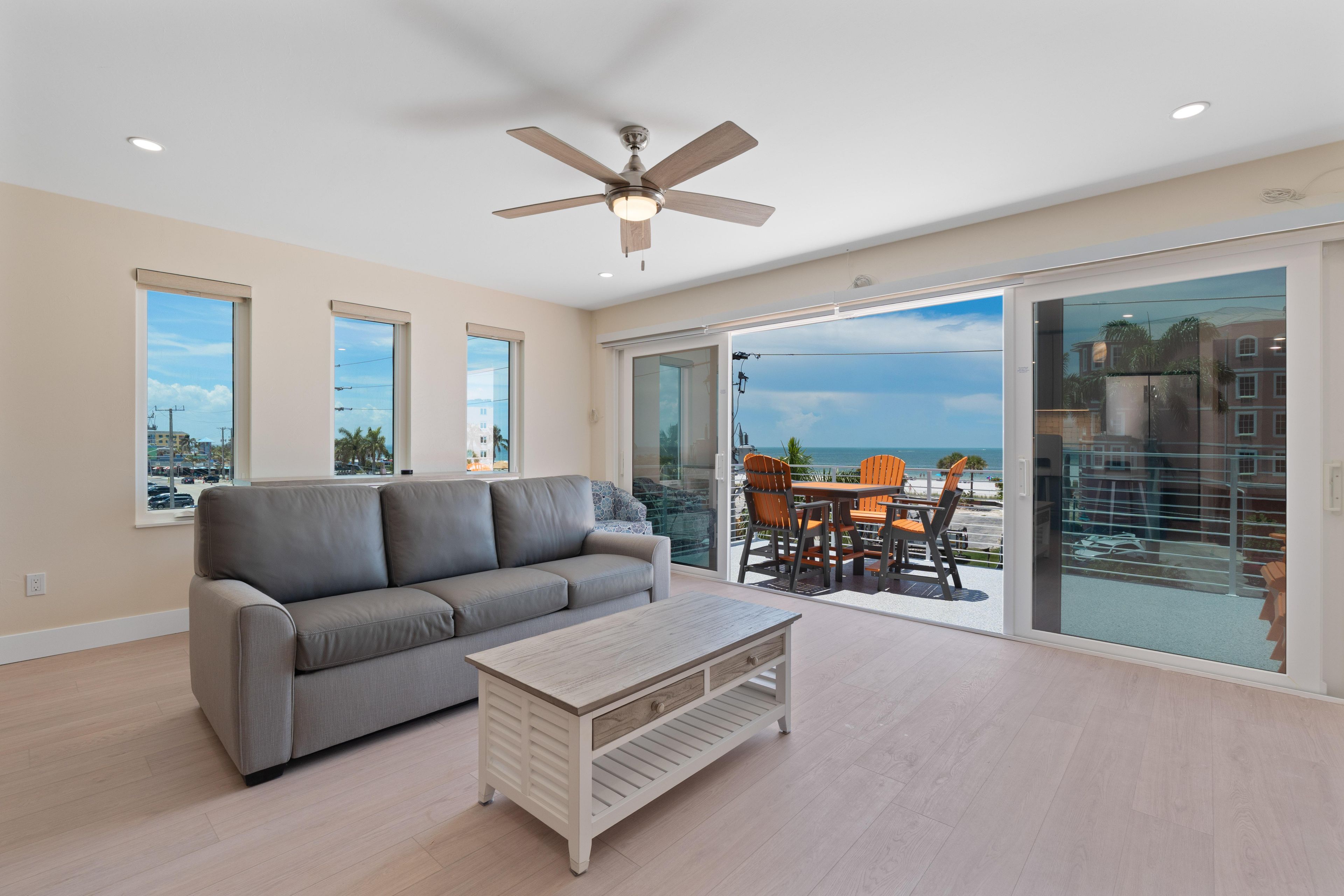 A modern living room with a grey sofa, a wooden coffee table, and a ceiling fan.