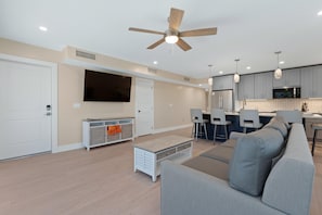 A modern living room with a sofa, a television, and a ceiling fan. - Salty Seahorse (Fort Myers Beach)