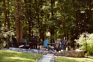 Un espace extérieur aménagé avec des chaises Adirondack et un mur en pierre.