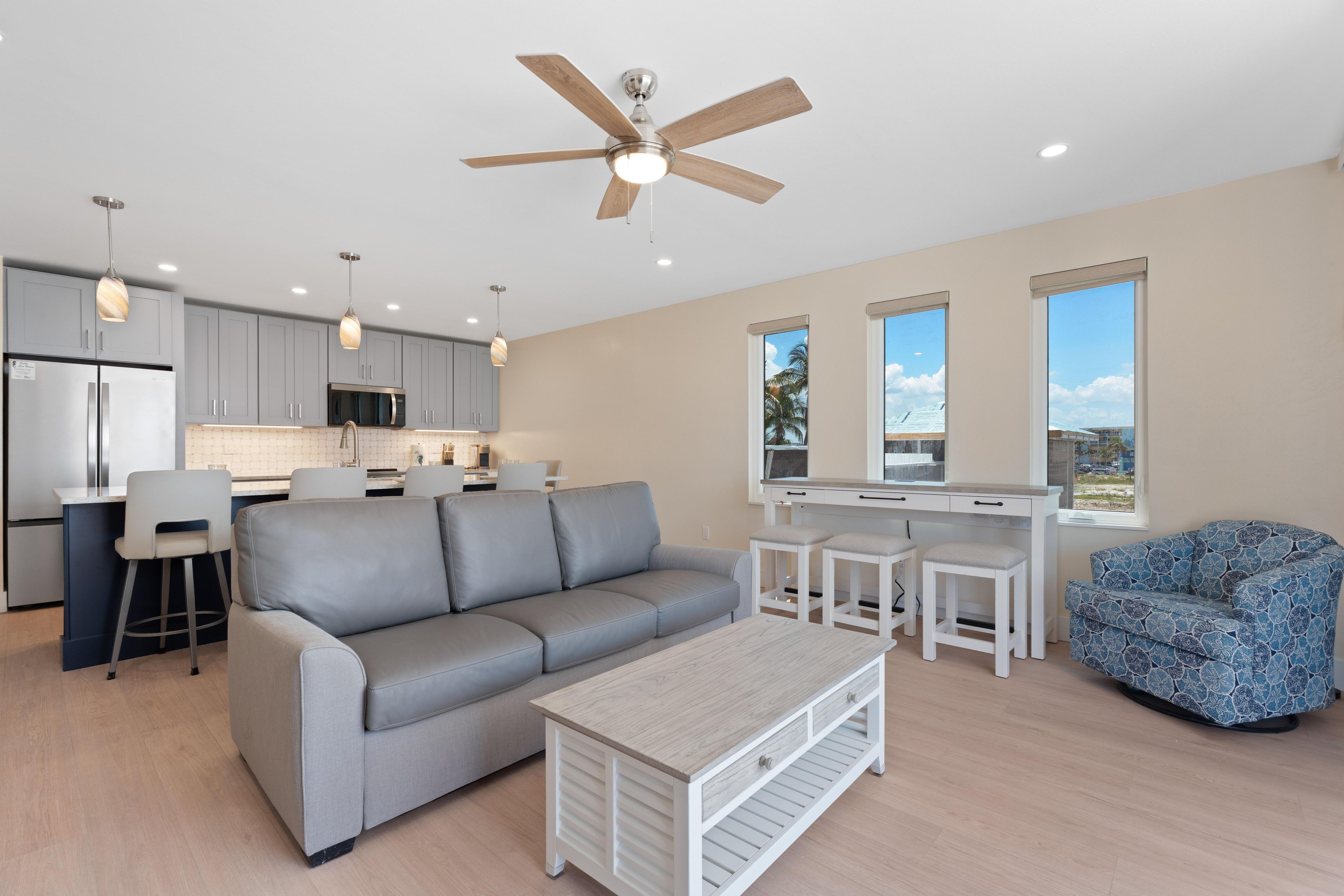 A modern kitchen with a built-in microwave, a grey sofa, and a dining area with a white table and chairs.