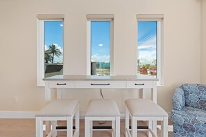 A room with a white desk, three windows, and a bench. - Salty Seahorse Unit 100 (Fort Myers Beach)