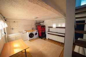 A laundry room with a washing machine, dryer, and ironing board. - House for 4 people near the GR34 – Pink Granite Coast – near Perros-Guirec (Trélévern)
