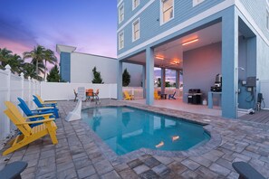 A swimming pool with lounge chairs, a barbecue area, and a covered patio. - Salty Seahorse Unit 200 (Fort Myers Beach)