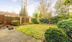 A backyard with a wooden fence, a lawn, and various plants. - West London Period Property w Access to Airports and Central London (London)