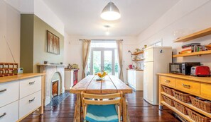 A compact kitchen with a wooden table, chairs, a refrigerator, and a microwave. - West London Period Property w Access to Airports and Central London (London)