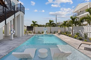 A swimming pool with lounge chairs, a white fence, and palm trees. - Calico Jack's Lookout (Fort Myers Beach)
