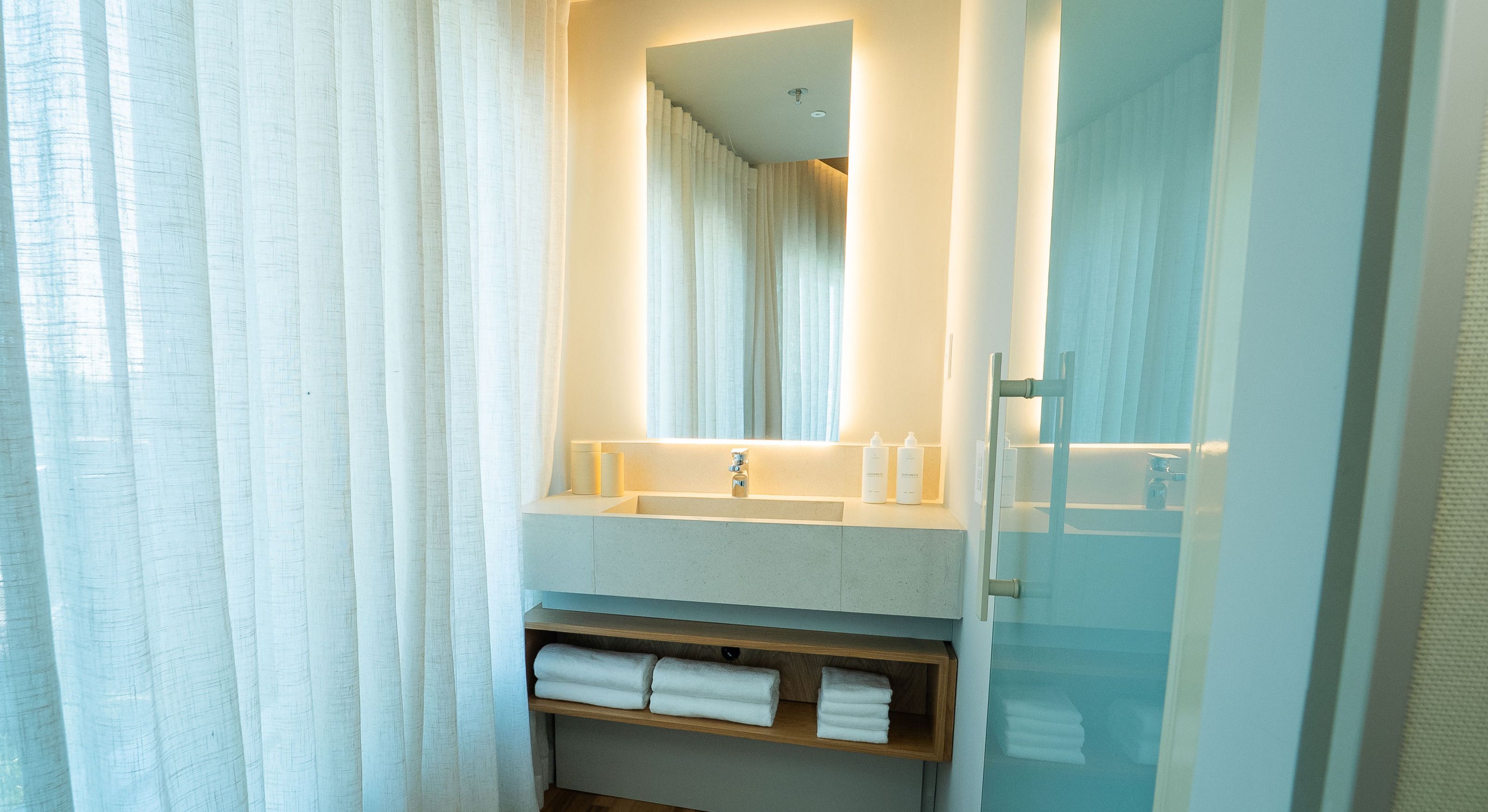 A modern bathroom with a large mirror, a sink, and a towel rack.