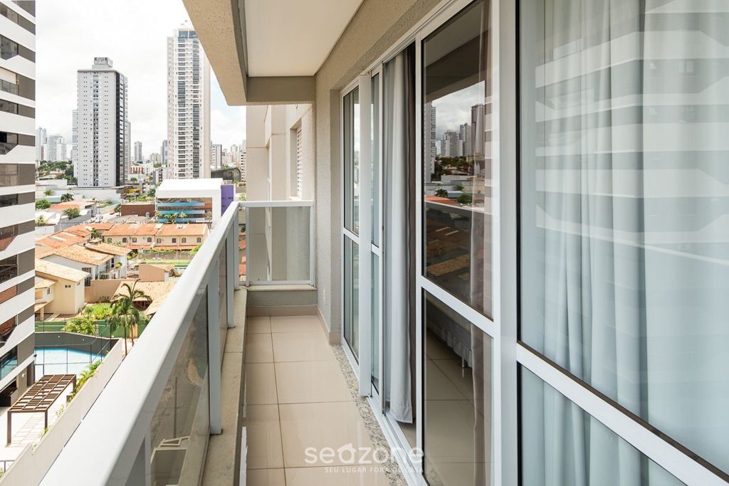 A balcony with a city view, large windows, and a tiled floor.