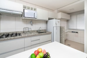 A modern kitchen with white cabinets, a granite countertop, a microwave, a sink, and a refrigerator. - Flat in a Cond. With Pool, Setor Bueno - Txp0807 (Goiânia)