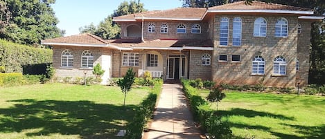 A two-story stone house with a central entrance, a covered porch, and a well-maintained lawn.
