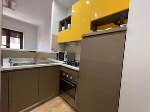 Cuina amb rentatge, fogó, forn i armaris superiors de color groc.
