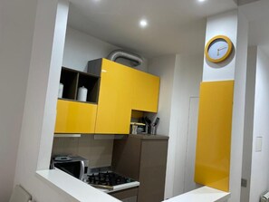Una cocina con armarios amarillos, microondas y cocina a gas.