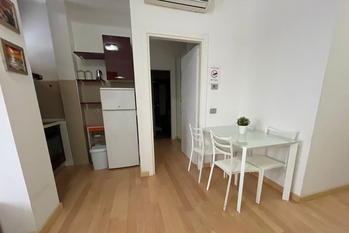 A compact living space with a kitchenette, a dining area with a table and chairs, and a small potted plant.