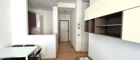 Un interior moderno con comedor, cocina y pasillo que conduce a una puerta.