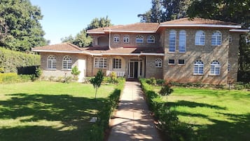 A two-story stone house with a central entrance, a covered porch, and a well-maintained lawn.