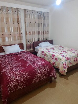 Habitació amb dos llits, cada un amb un estenat diferent.