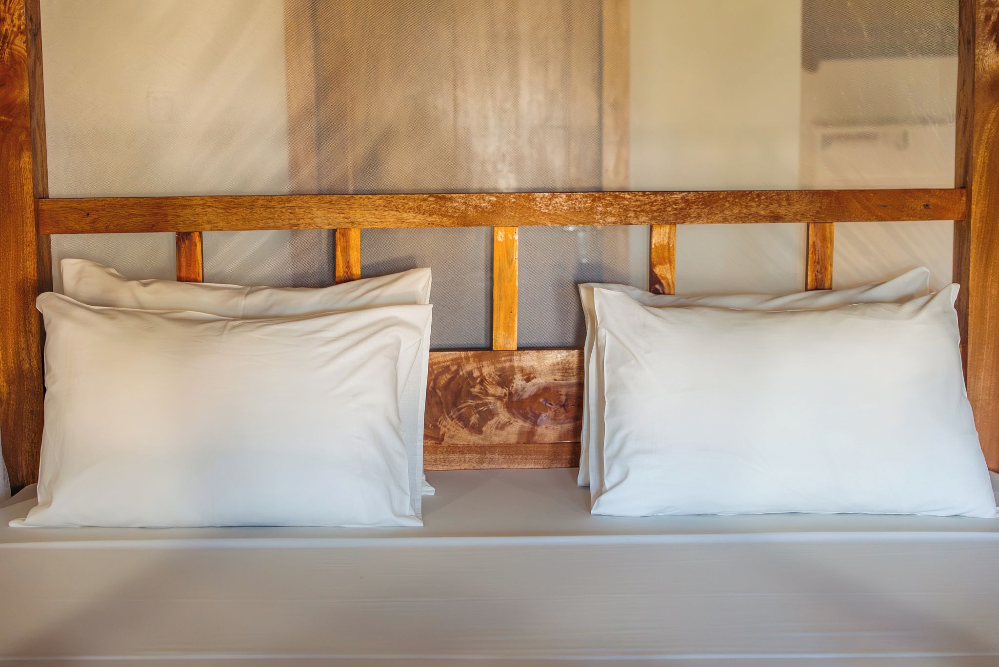 Een tweepersoonsbed met een houten hoofdbord en twee kussens.