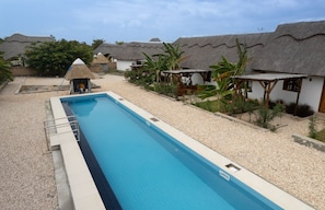 A swimming pool with a thatched-roof structure in the background. - Romantic Villa Near Beach - AC, WiFi, Kitchen (Pwani Mchangani North Region)