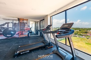 A home gym with treadmills, a weight bench, and a wall with fitness equipment illustrations. - Apt in Bldg w/ Pool, 280m From Beach Clf0104 (Salvador)