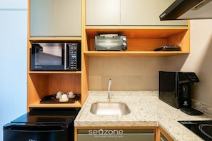 A compact kitchenette with a microwave, toaster, and coffee maker on wooden shelves, a stainless steel sink, and a dishwasher. - Apt in Bldg w/ Pool, 280m From Beach Clf0104 (Salvador)