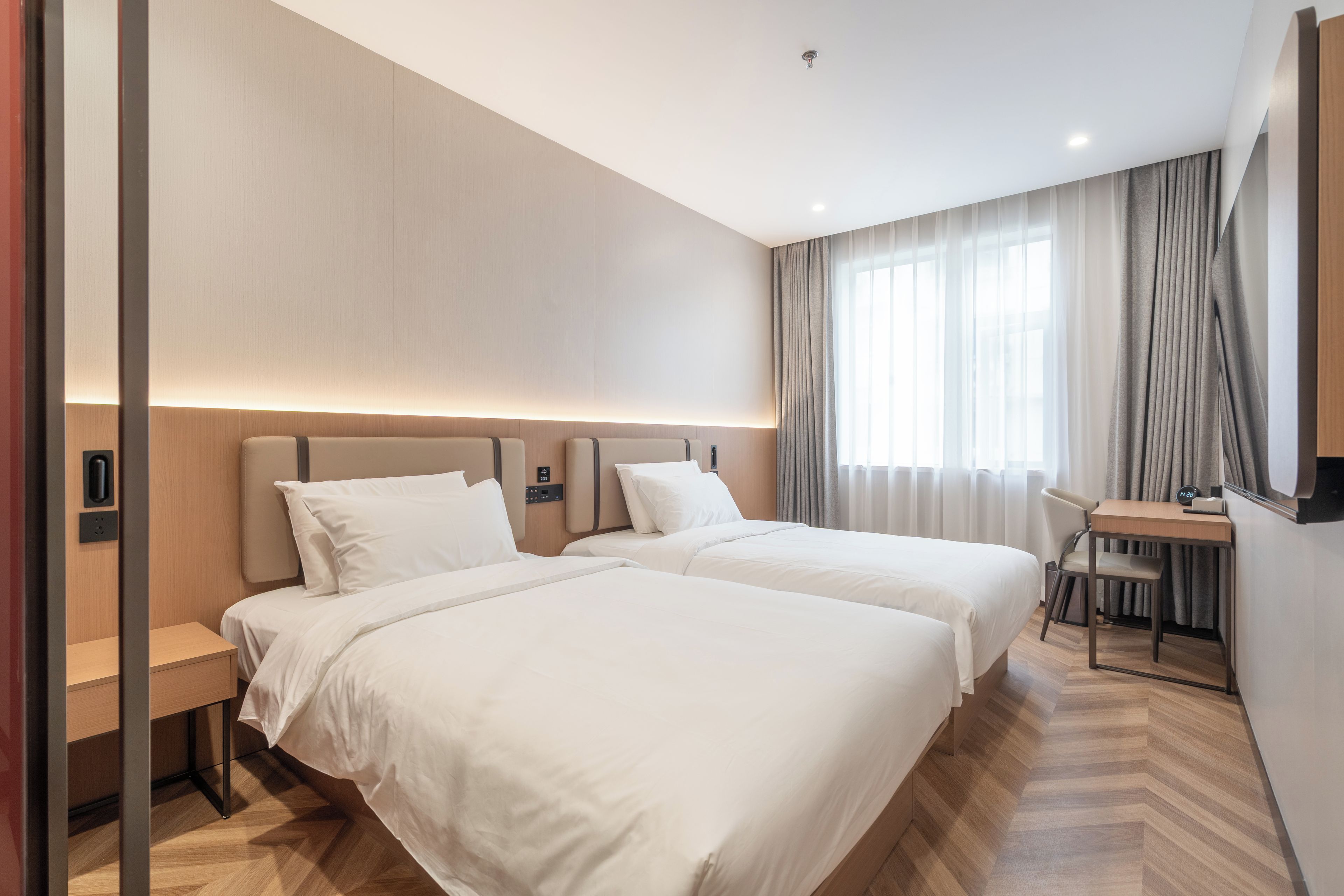 Quarto de hotel com duas camas, uma escrivaninha e uma cadeira.